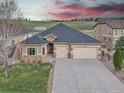 Stucco home featuring a two-car garage, stone accents, and well-maintained lawn at 9754 W Ontario Pl, Littleton, CO 80128