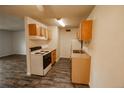 Well-lit kitchen with wood-look flooring, white appliances, and light wood cabinets at 10211 Ura Ln # 9-308, Thornton, CO 80260