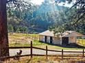 Scenic barn surrounded by a white fence, offering a serene and pastoral setting for equestrian pursuits at 3841 Myers Gulch Rd, Kittredge, CO 80457