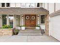 Close-up of the entrance featuring a double wooden door with decorative wreaths and manicured landscaping at 7703 S Grape Ct, Centennial, CO 80122