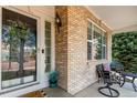 Inviting front porch with brick accents, a cozy seating area, and a decorative wreath on the front door at 7852 Solstice Way, Castle Rock, CO 80108