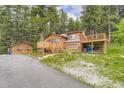 Exterior view of log cabin with detached living space and spacious deck surrounded by lush greenery at 8758 S Murphy Gulch Rd, Littleton, CO 80127