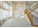 Bright living room boasts soaring ceilings, large windows, elegant chandelier, and staircase with wooden handrail at 510 Fairhaven St, Castle Rock, CO 80104