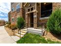 Condo front entrance featuring well-lit steps, stone accents, and a small front porch at 9185 Wilde Ln # 101, Parker, CO 80134