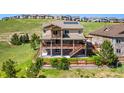 Spacious backyard featuring a large deck, a stone patio, and a well-manicured lawn at 17102 W 85Th Pl, Arvada, CO 80007