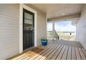 Charming covered porch with wood flooring, a black front door, and a view of the property's expansive surroundings at 1465 Arabian Trl, Elizabeth, CO 80107