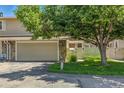 Two-car garage on exterior of home has green grass and mature tree in the front yard at 3274 S Heather Gardens Way, Aurora, CO 80014