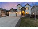 Charming two-story home featuring a three-car garage and a welcoming stone-accented entrance at dusk at 228 Horizon Ave, Erie, CO 80516