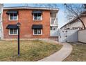 Charming brick exterior featuring black window awnings, manicured lawn, and pathway leading to the entrance at 160 Jackson St # 5, Denver, CO 80206