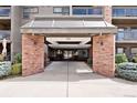 The condo building entrance has a glass awning, brick pillars, and a well-lit entryway for welcoming residents and visitors at 350 Detroit St # 107, Denver, CO 80206