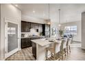 Modern kitchen with dark cabinets, white countertops, stainless steel appliances, and dining area at 917 W 129Th Pl, Denver, CO 80234