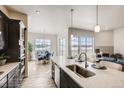 Bright kitchen island with stainless steel sink, dark cabinets, and open dining and living area at 917 W 129Th Pl, Denver, CO 80234