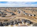 Aerial view of a suburban neighborhood showcasing winding streets, residential homes, and open fields at 6664 Merrimack Dr, Castle Pines, CO 80108