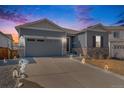 Inviting exterior of a well-lit home with a concrete driveway, showcasing stone accents and a two-car garage at 6664 Merrimack Dr, Castle Pines, CO 80108