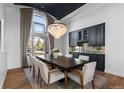 Elegant dining room boasts large windows, a stunning chandelier and dark cabinetry at 948 Buffalo Ridge Rd, Castle Pines, CO 80108