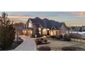 Elegant home with a well-maintained lawn, mature trees, and a circular driveway leading to a three-car garage at 948 Buffalo Ridge Rd, Castle Pines, CO 80108