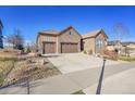 Lovely stone home with a three-car garage and well-maintained landscaping, showcasing curb appeal at 27655 E Moraine Dr, Aurora, CO 80016