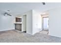 Open concept living room with neutral carpet, breakfast bar, ceiling fan, and view of the front door at 7185 S Gaylord St # A, Littleton, CO 80122