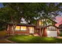 Charming two-story brick home with well-maintained lawn and mature trees in the evening at 13052 W Asbury Pl, Lakewood, CO 80228