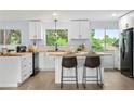 Bright, modern kitchen with butcher block countertops, an island with seating, and views of the backyard at 13052 W Asbury Pl, Lakewood, CO 80228