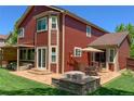 Red home featuring a stone patio with a fire pit, outdoor seating and a lush lawn at 6040 W Prentice Ave, Littleton, CO 80123