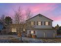 Two-story home with brick and siding, featuring a well-manicured lawn and a two-car garage, bathed in the soft glow of twilight at 7009 S Forest Ct, Centennial, CO 80122