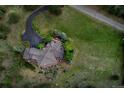 Aerial view of a brown roofed home with stone accents, patio, and landscaping surrounded by green lawns at 2191 Baldy Ln, Evergreen, CO 80439