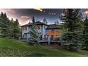 Exterior of a gray home with a deck, large windows, and lush green landscaping at 2191 Baldy Ln, Evergreen, CO 80439
