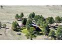Aerial view showcases the back of a home nestled in a grassy, tree-filled landscape, offering privacy and natural beauty at 1740 Michael Gates Dr, Parker, CO 80138