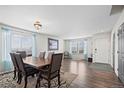 Bright dining room features a modern light fixture, wood floors, and large windows with lovely blue curtains at 4797 Longs Peak St, Brighton, CO 80601