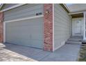 Spacious garage with gray door and brick accents, seamlessly integrated into the home's facade at 9659 Autumnwood Pl, Highlands Ranch, CO 80129