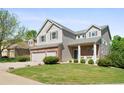 Two-story home with brick accents, gray siding, landscaped front yard, and an attached two-car garage at 10511 Jaguar Gln, Lone Tree, CO 80124