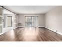 Open concept living room with hardwood floors and sliding doors to carpeted bedroom and balcony at 14050 E Linvale Pl # 309, Aurora, CO 80014