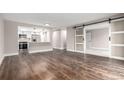 Open living area with hardwood floors and sliding barn door to carpeted bedroom at 14050 E Linvale Pl # 309, Aurora, CO 80014