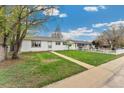 Single-story home featuring a lush green lawn, sidewalk, and mature trees under a partly cloudy sky at 701 Emporia St, Aurora, CO 80010