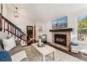 Cozy living room featuring a brick fireplace, dark wood floors, and staircase access to upper levels at 517 Chiswick Cir, Highlands Ranch, CO 80126