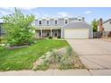 Inviting two-story home showcasing a well-manicured lawn, mature trees, and a spacious driveway leading to a garage at 225 Berthoud Way, Golden, CO 80401