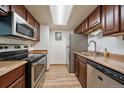The kitchen features stainless steel appliances, brown cabinetry and wood-look flooring at 8555 Fairmount Dr # A108, Denver, CO 80247