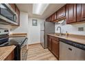 The kitchen features stainless steel appliances, brown cabinetry and wood-look flooring at 8555 Fairmount Dr # A108, Denver, CO 80247