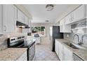 Bright kitchen featuring granite countertops, white cabinets, and stainless steel appliances at 3175 W Stanford Ave, Englewood, CO 80110