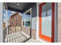 Inviting porch with brick accents, a modern railing, and a bright orange front door at 21295 E 61St Dr, Aurora, CO 80019