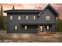 Charming two-story grey home with a woodpile near the entrance and beautiful twilight sky at 379 Rainbow Rd, Idaho Springs, CO 80452