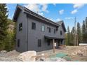 Two-story grey mountain home highlighting the landscaping and proximity to the forest at 379 Rainbow Rd, Idaho Springs, CO 80452