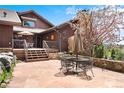 Inviting back patio with stone flooring, seating, and a view of flowering trees at 2851 Interlocken Dr, Evergreen, CO 80439