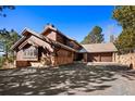 Stunning exterior of a rustic, wood-clad home with a stone foundation and a multi-car attached garage at 2851 Interlocken Dr, Evergreen, CO 80439