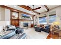 Spacious living room with exposed wood beams, stone fireplace, and large windows showcasing a scenic view at 4502 Echo Cliff Ln, Larkspur, CO 80118