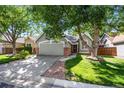 Green house exterior with a two-car garage and well-maintained lawn at 2279 S Joliet Way, Aurora, CO 80014