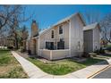 Exterior view of a charming two-story townhouse featuring a stone chimney and private patio at 2699 S Xanadu Way # A, Aurora, CO 80014