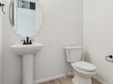 Clean half-bathroom featuring a pedestal sink, toilet, and modern fixtures at 8205 Cokedale Cir, Littleton, CO 80125
