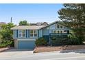 Charming exterior of a light-blue home featuring a well-maintained front yard and an attached garage at 310 S Alkire St, Lakewood, CO 80228